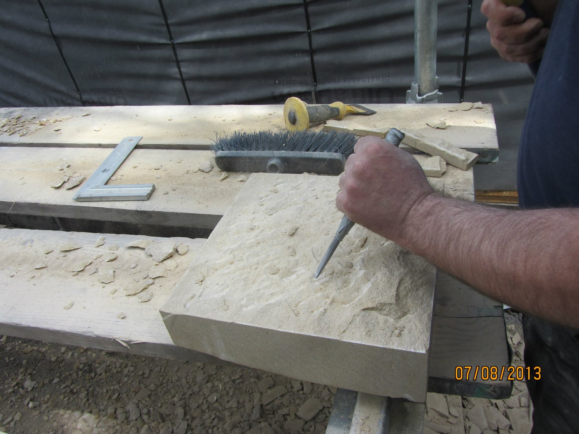 Hand carving natural stone with stonemasonry tools for Edinburgh stonework projects.
