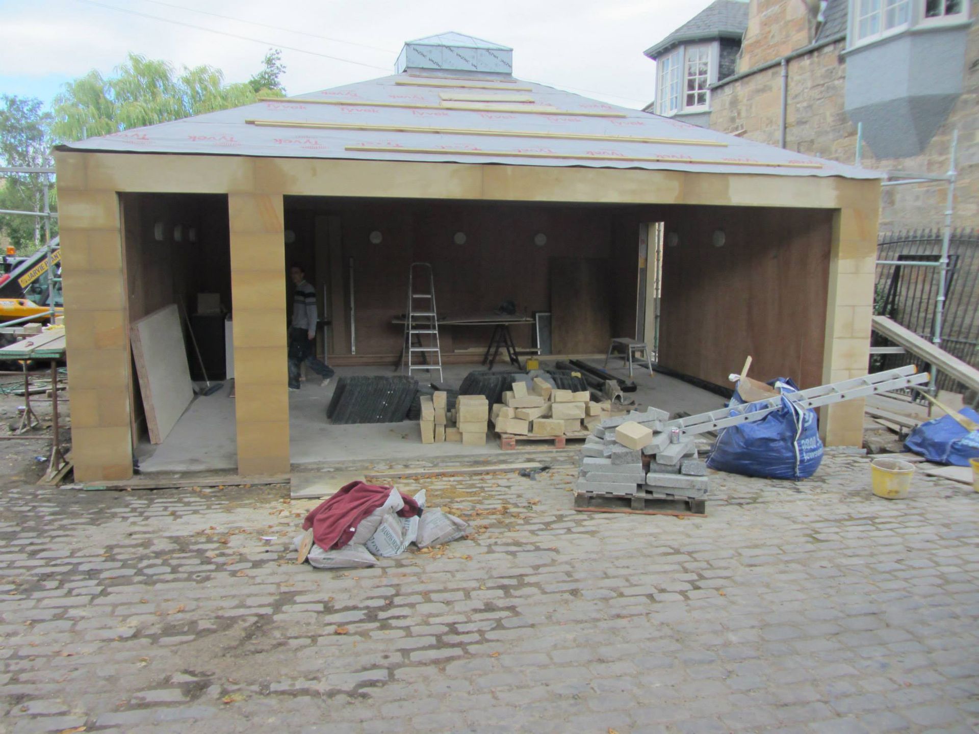 Traditional Scottish stone masons working on a building extension, showcasing craftsmanship in stonework and masonry construction.