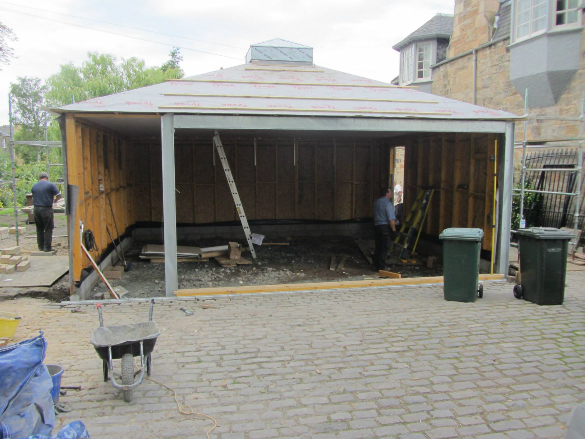 Craftsmen building a stone feature in a garden, showcasing expert stone masonry and conservatory construction skills.
