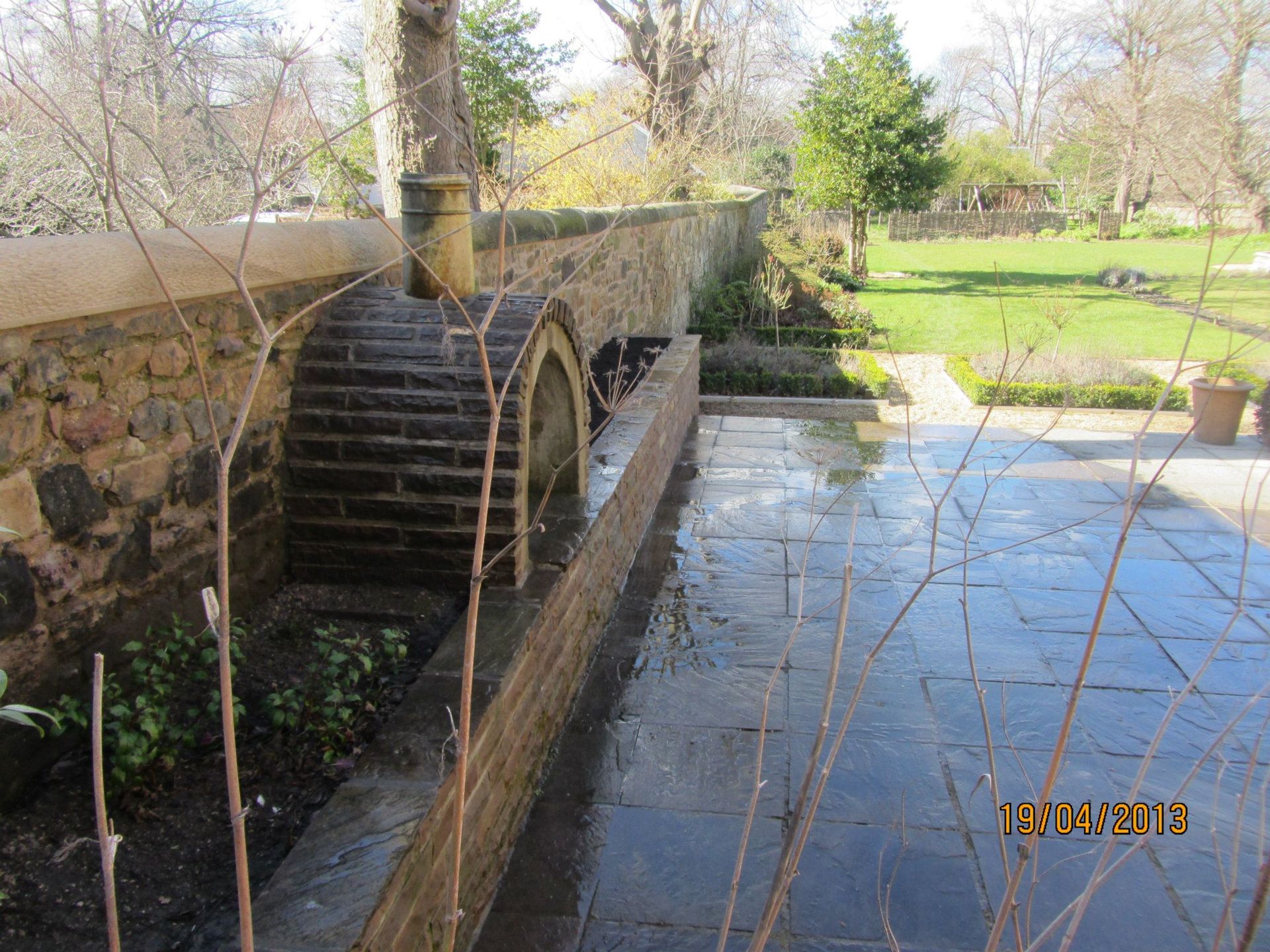 Traditional Edinburgh stone wall with water feature and paved garden area.